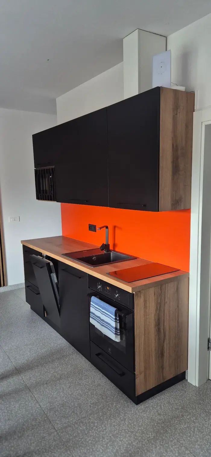 Kuchyňka s oranžovou zástěnou a černými skříňkami