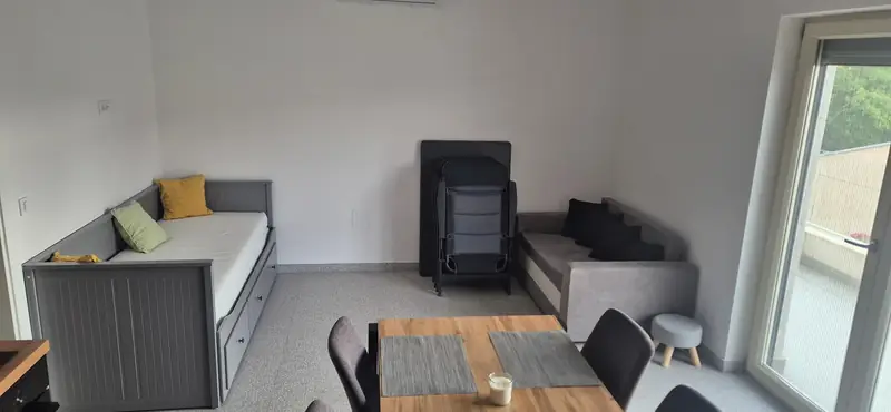 Obývací pokoj s rozkládací postelí, gaučem a jídelním stolem